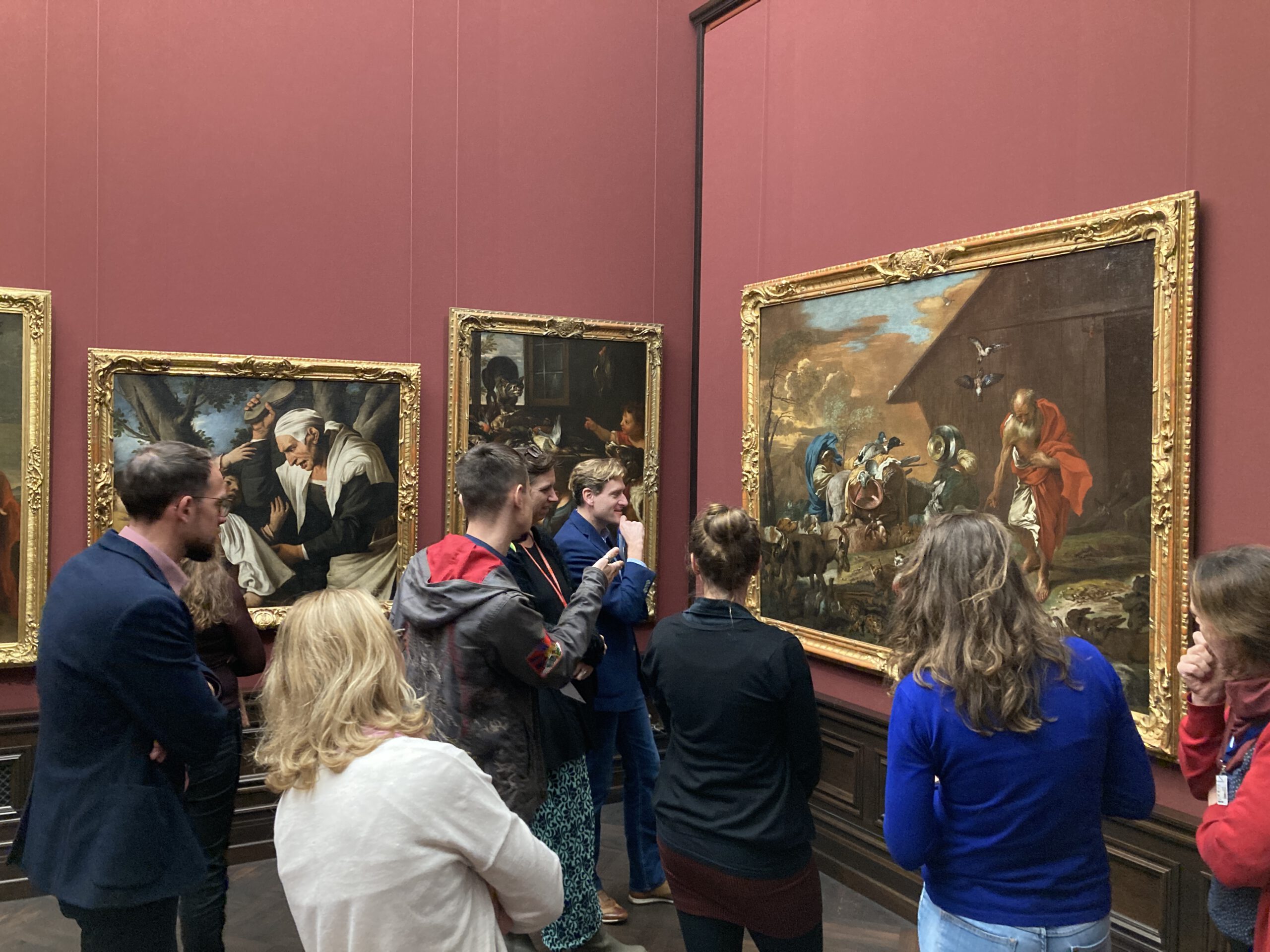 Interessierte Erwachsene schauen sich Gemälde in einer Kunstgalerie an.