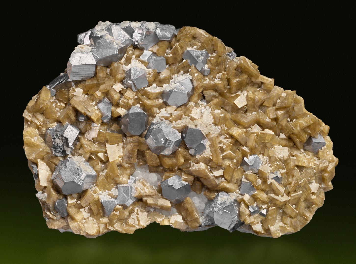 stahlgraue Galenitkristalle im sogenannten Neudorfer Typ, einer Kombination aus Würfel, Oktaeder und Rhombendodekaeder sitzen zwischen strohgelben Sideritkristallen auf einer circa 12,5 cm breiten Stufe