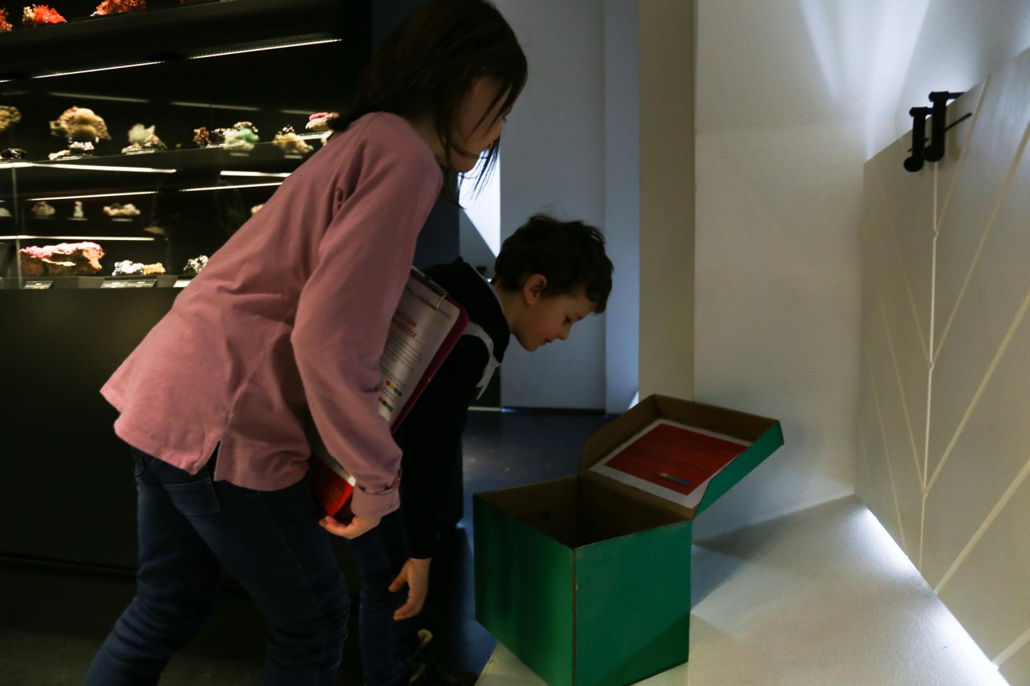 Kinder suchen in der Ausstellung einen geheimen Code in einer geheimnisvollen Kiste.