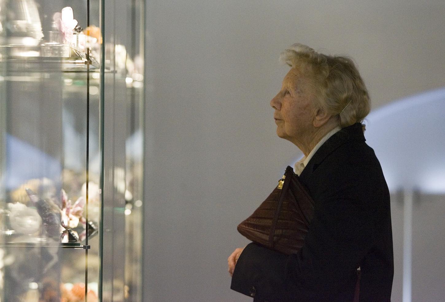 Eine ältere Dame trägt eine Handtasche unter ihrem Arm. Sie ist im Profil zu sehen und blickt in eine Vitrine. Die Dame ist Dr. Erika Pohl-Ströher.