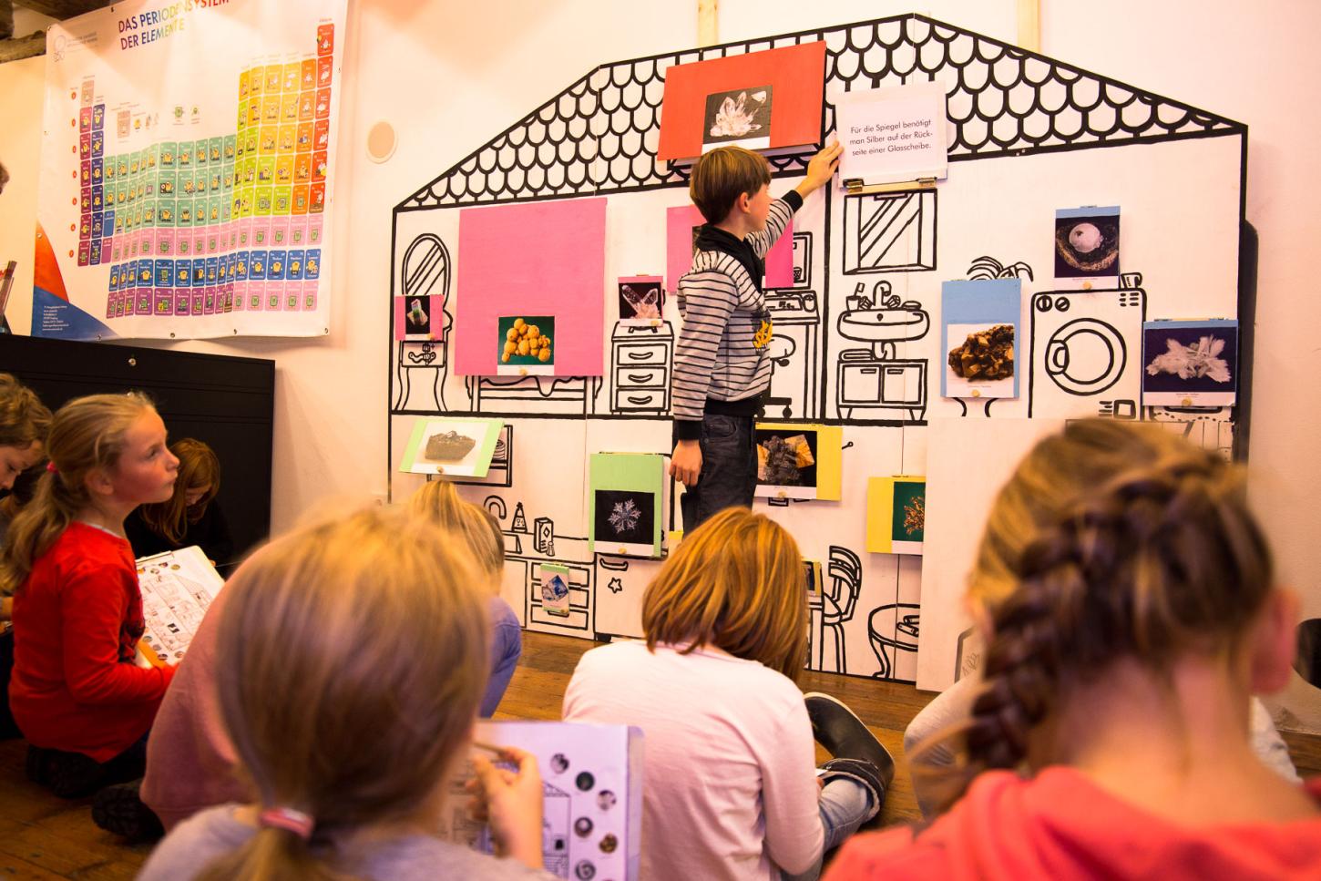 Eine Kindergruppe untersucht das Klappenhaus.