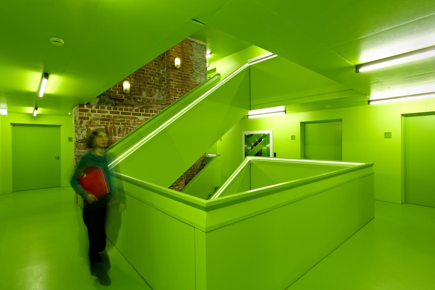 In einem grünen Treppenhaus läuft ein Person.